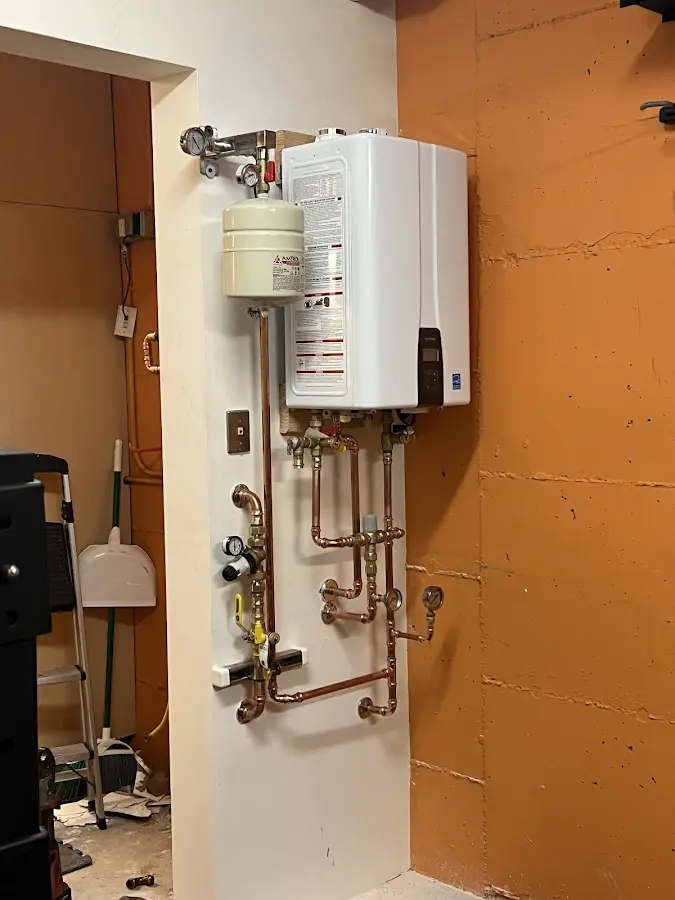 Plumbing technician inspecting water heater connections in River Edge